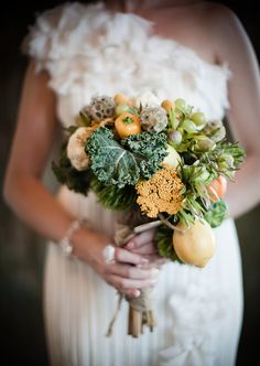 a bride holding a bouquet of flowers and fruit