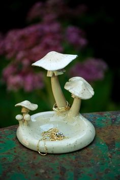 two small mushrooms sitting on top of a table next to some purple and white flowers