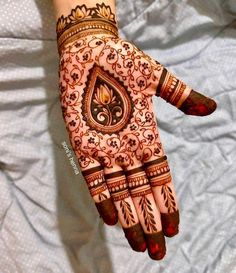 a henna on someone's hand that is decorated with flowers and leaves,