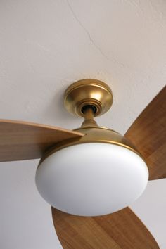 a ceiling fan with a light on it in a room that has white walls and wood trim