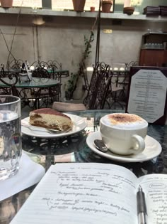 there is a cup of coffee and a cake on the table with an open book