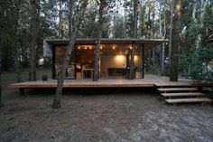 a small cabin in the woods with stairs leading up to it