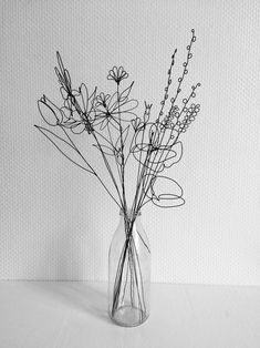 black and white photograph of dried flowers in a glass vase on a countertop with textured background