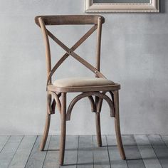 a wooden chair sitting in front of a wall with a framed painting on it's side