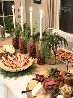 a table topped with lots of different types of food and candles on top of it