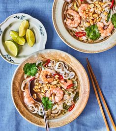 two bowls of shrimp noodle soup with chopsticks and lime slices on the side