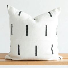 a black and white pillow sitting on top of a wooden table