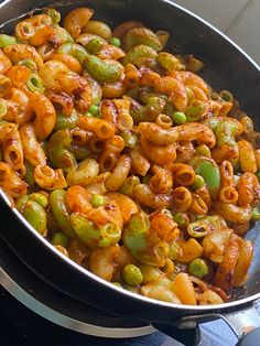 a pan filled with pasta and peas on top of a stove