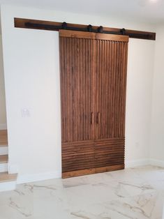 an empty room with white walls and wooden doors in the center, along with marble flooring