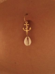 a pair of earrings with an anchor and seashell hanging from the back of a woman's stomach