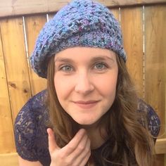 a woman wearing a blue knitted hat and making the peace sign with her hand