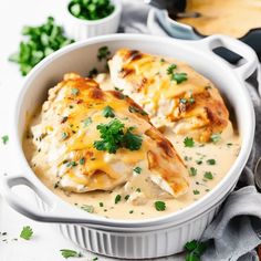 two chicken enchiladas in a white casserole dish with parsley on top