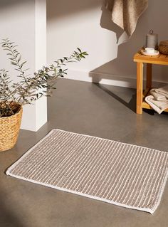 a white rug sitting on top of a floor next to a potted plant