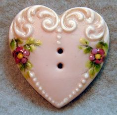 a white heart shaped brooch with flowers on it