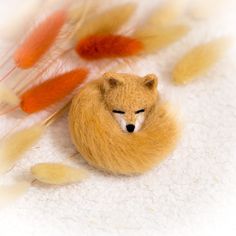 a stuffed animal sleeping on top of white fluffy material with feathers in the back ground