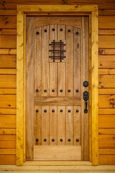 a close up of a wooden door on a building with wood paneling and metal hardware