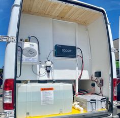 the back end of a white van with an electronic device in it's trunk