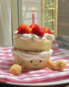 a piece of cake with strawberries on top is sitting on a pink and white checkered plate