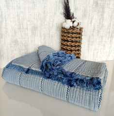 two blue towels sitting on top of each other next to a basket with cotton balls