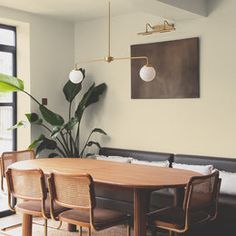 a dining room table and chairs in front of a large window with potted plants