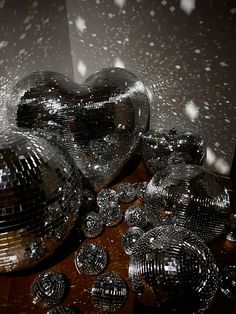 two shiny disco balls sitting next to each other on top of a wooden table covered in confetti