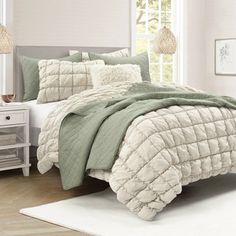 a bedroom with white walls and light green comforter on the bed, along with two nightstands