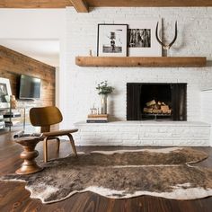 a living room with a white brick fireplace and wooden floors