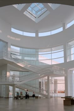 two people sitting on benches in the middle of a large building with skylights overhead