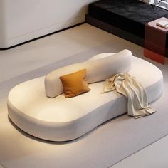 a large white couch sitting on top of a floor next to a table and chair