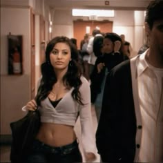 a man and woman are walking down the hallway in an office building, with other people behind them