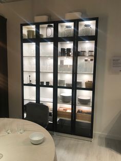 an empty dining room table and chairs in front of a glass display case