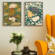 there are two paintings on the wall next to a chair and vase with flowers in it