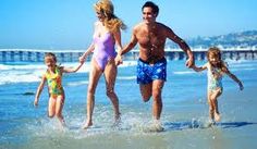 a man and two children are running in the water at the beach with their parents