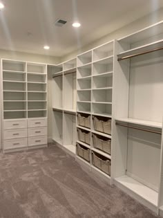 an empty walk in closet with white shelving and baskets on the shelves, carpeted floor