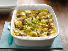 a casserole dish with meat and vegetables in it on a blue place mat