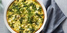 a casserole dish with spinach and cheese in it on a blue cloth