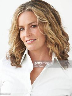 a woman with blonde hair smiling and looking at the camera, wearing a white shirt