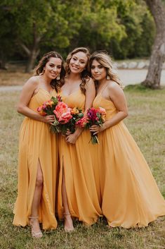 three bridesmaids in yellow dresses posing for the camera with their bouquets on