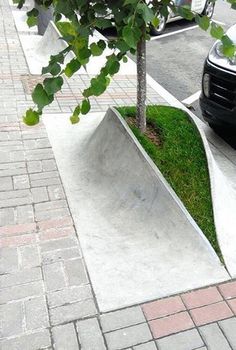 a skateboard ramp with grass growing in it on the sidewalk next to a parked car