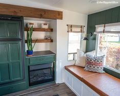 a kitchen with green cabinets and a window in the corner, next to a fireplace