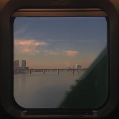 the view from inside an airplane looking out at water and buildings in the distance with a bridge across it