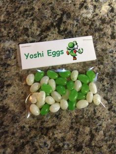 some green and white candies in a bag on a counter top next to a yoshi egg sign