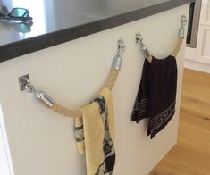 two towels hanging from hooks on the wall next to a counter with eyeglasses