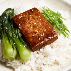 a white plate topped with rice and meat next to green vegetables on top of it