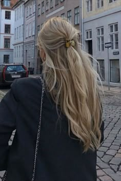 a woman is walking down the street with her cell phone in her hand and she has long blonde hair