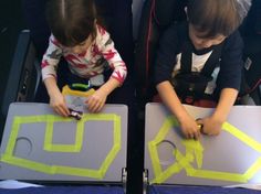 two young boys sitting on top of laptops with yellow tape around their necks and hands