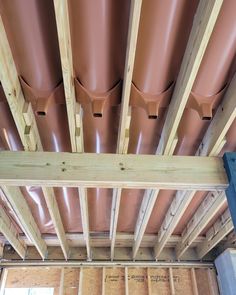 the inside of a house being built with wood framing and metal pipes on the ceiling