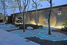 an outdoor area with trees and lights on the side of the building, along with stone walkways