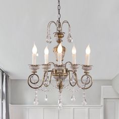 a chandelier hanging from the ceiling in a room with white walls and cabinets