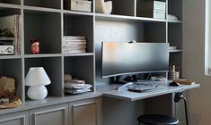 a desk with a computer on top of it in front of a book shelf filled with books